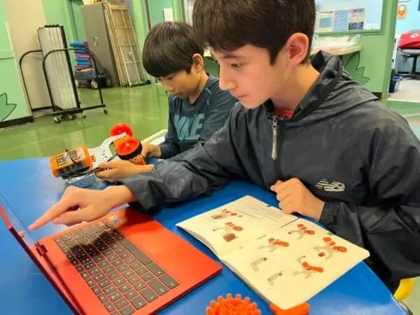 Students following a build guide at a laptop
